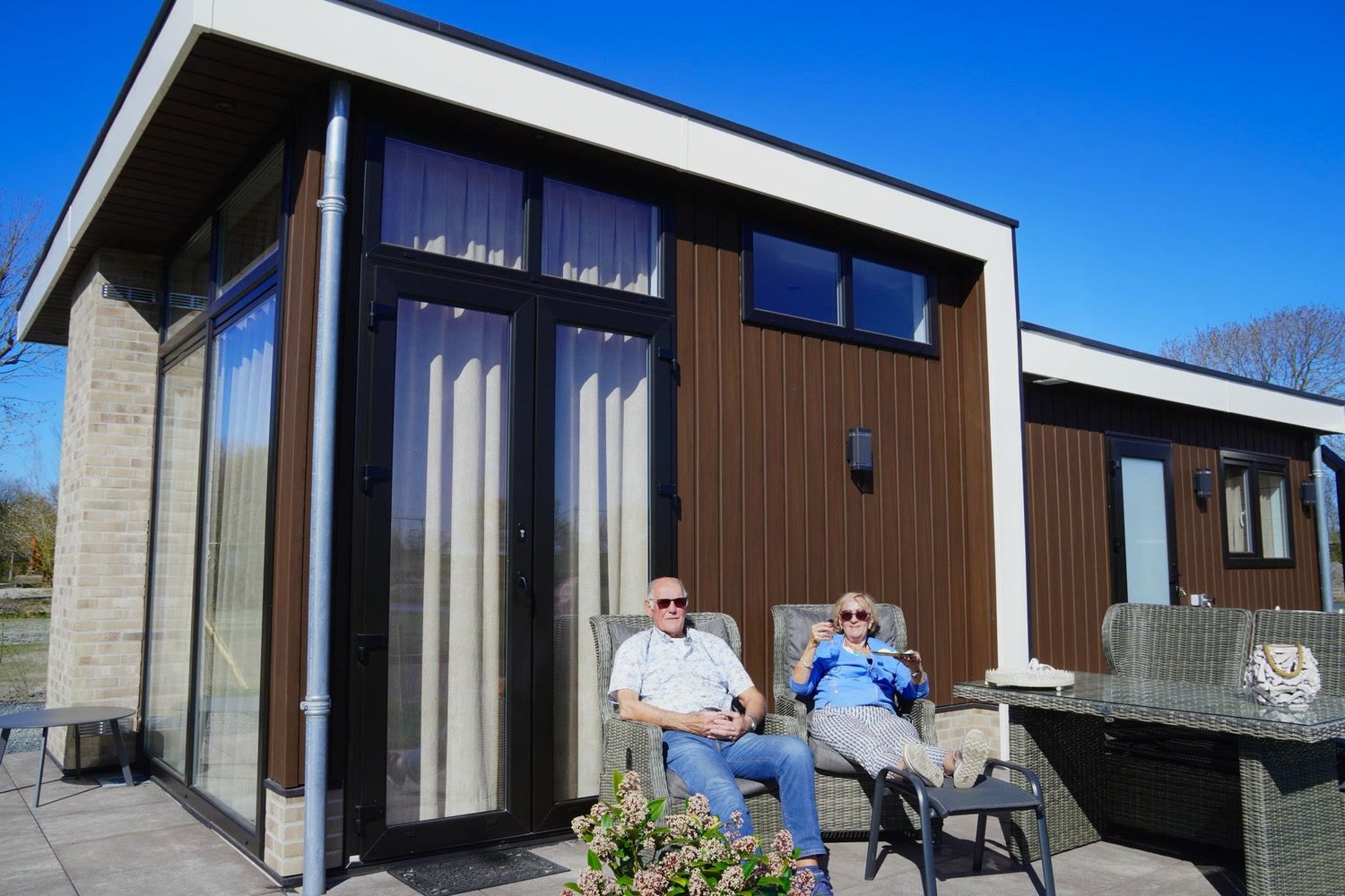 Kees en Kitty genieten in de zon op het terras van hun nieuwe woning in Waarland